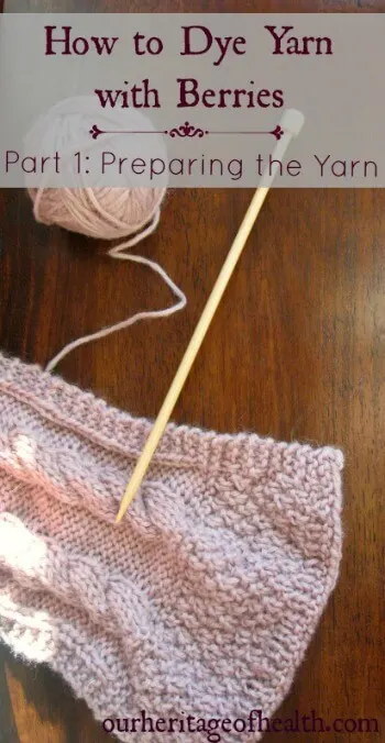 Ball of pale lavender colored yarn next to knitting needle and part of knitted scarf.