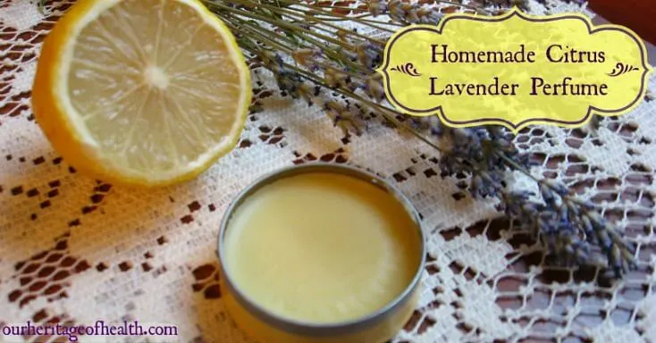 A tin of homemade solid perfume on a lace cloth with a cut lemon and sprigs of lavender beside it.