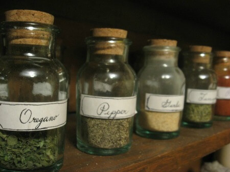 Cork-topped bottles of herbs and spices lined up on a shelf.
