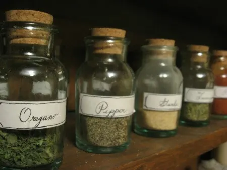 Cork-topped bottles of herbs and spices lined up on a shelf.