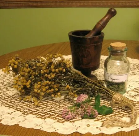 mortar and pestle with dried herbs and bottle of herbs
