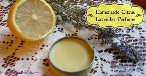 Tin of homemade perfume on a lace doily with a sliced lemon beside it and lavender sprigs.