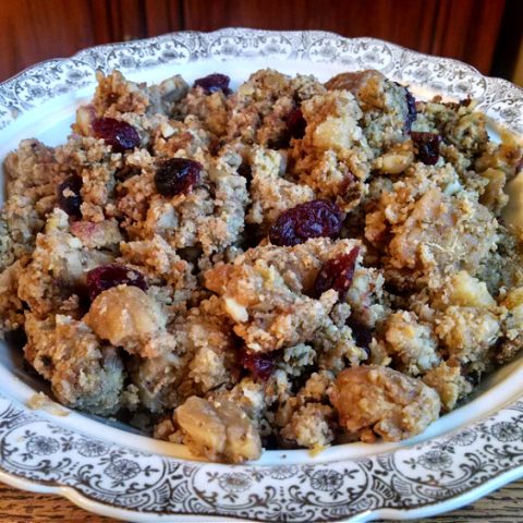 China bowl full of homemade stuffing with bread, cornbread, chestnuts, and dried cranberries.
