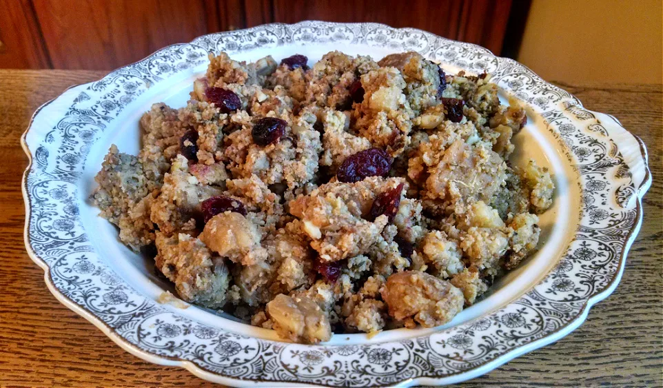 China bowl full of homemade stuffing with bread, cornbread, chestnuts, and dried cranberries.