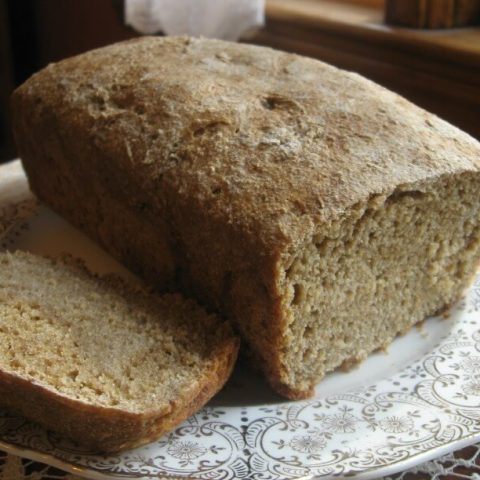 Loaf of sourdough bread on a plate with a slice cut off.