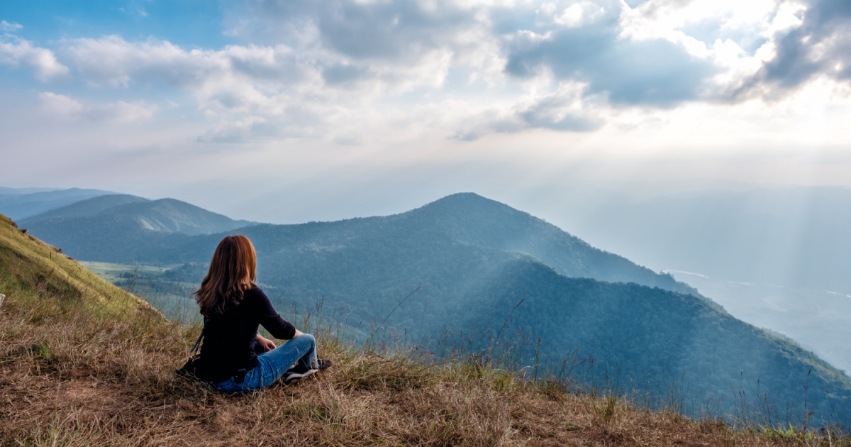 Woman on a hilltop looking out at the mountains.