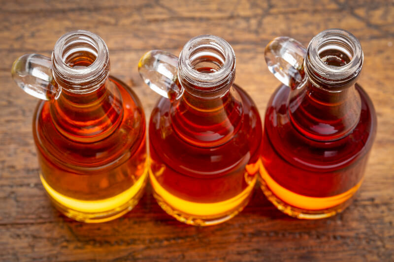 Three bottles of maple syrup lined up on a table.
