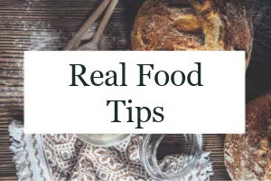 Loaf of bread on a table with spoons and sourdough starter with text overlay "Real Food Tips."