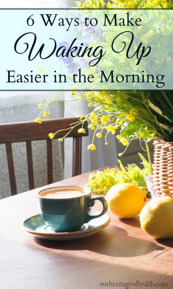 Cup of coffee in a teal blue cup with lemons and flowers on a table by a window in the morning sunlight.
