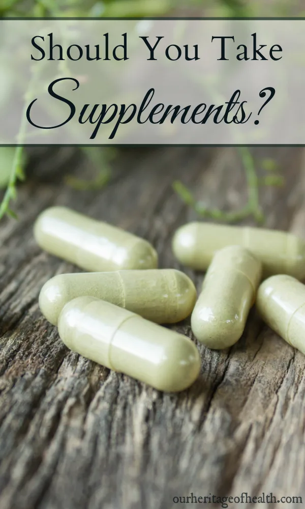 Supplement capsules on a wooden table with green leaves in the background.