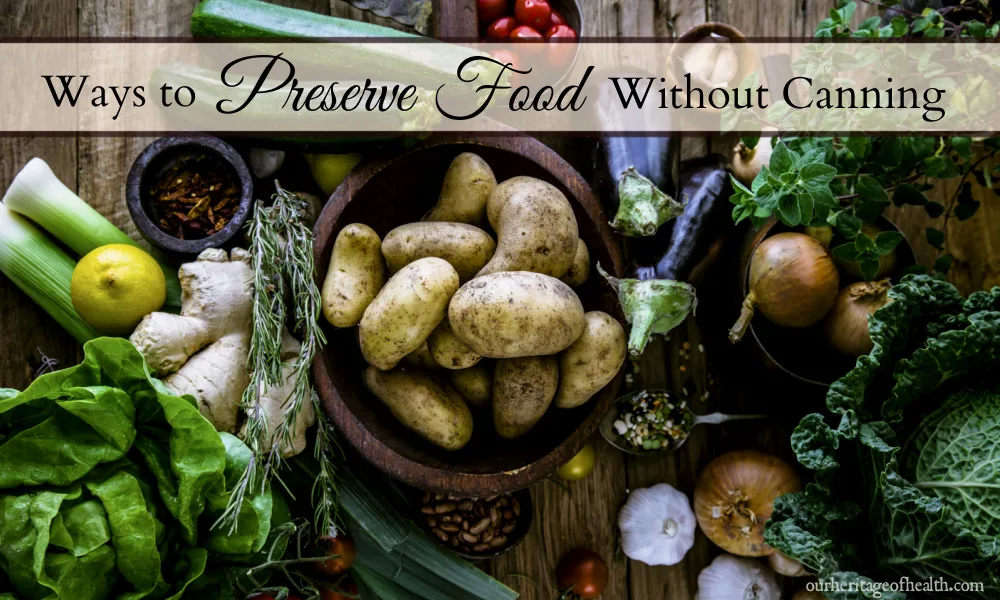 A variety of fresh vegetables and herbs on a wooden table including potatoes, cabbage, oregano, onions, garlic, lettuce, tomatoes, etc.