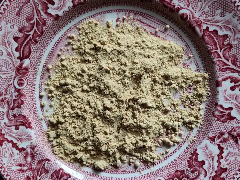 Dried ground ginger root on a red China plate.